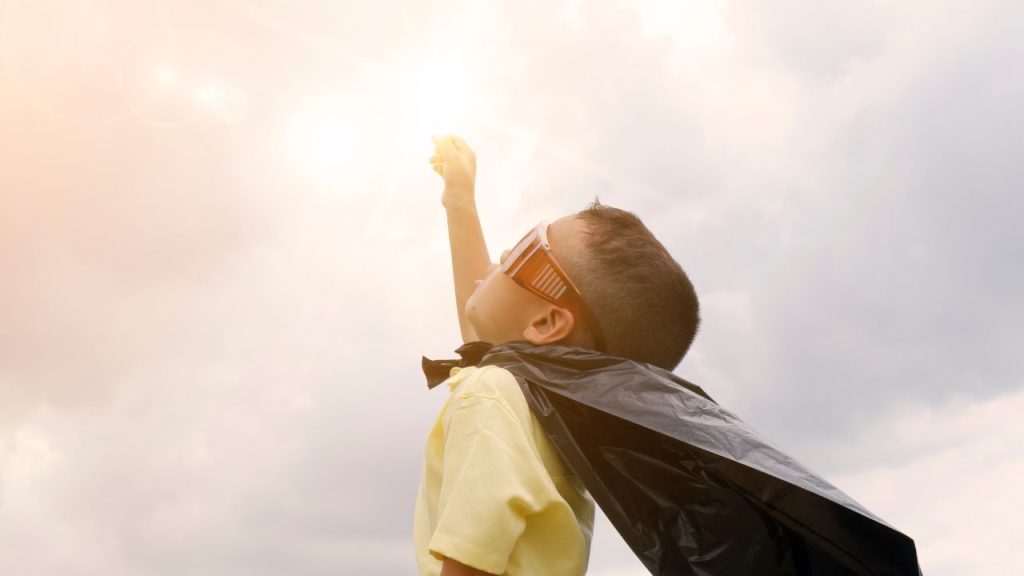 ヒーローの格好をして天を仰ぐ男の子