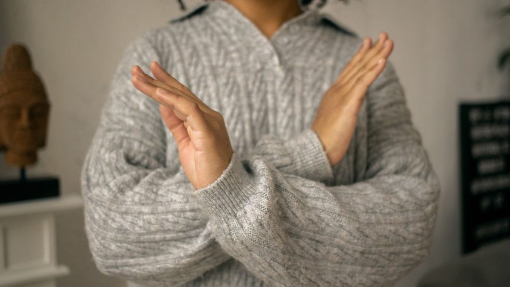 手でばつ印を作っている女性