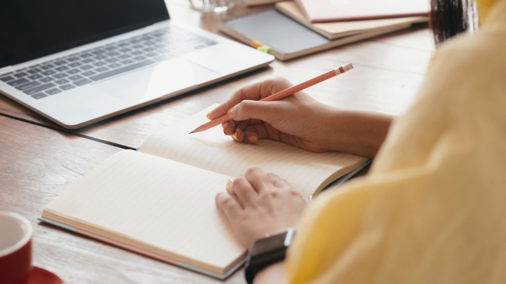 パソコンとノートを使って勉強をしている女性