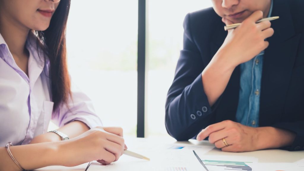 オフィスで資料を使って相談をしている会社員