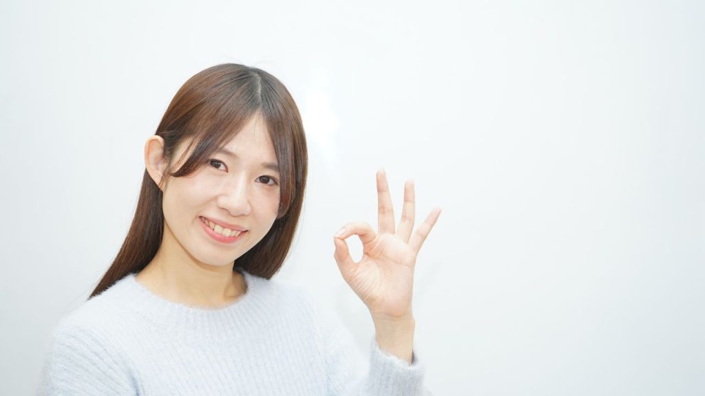 指でOKサインを出している女性