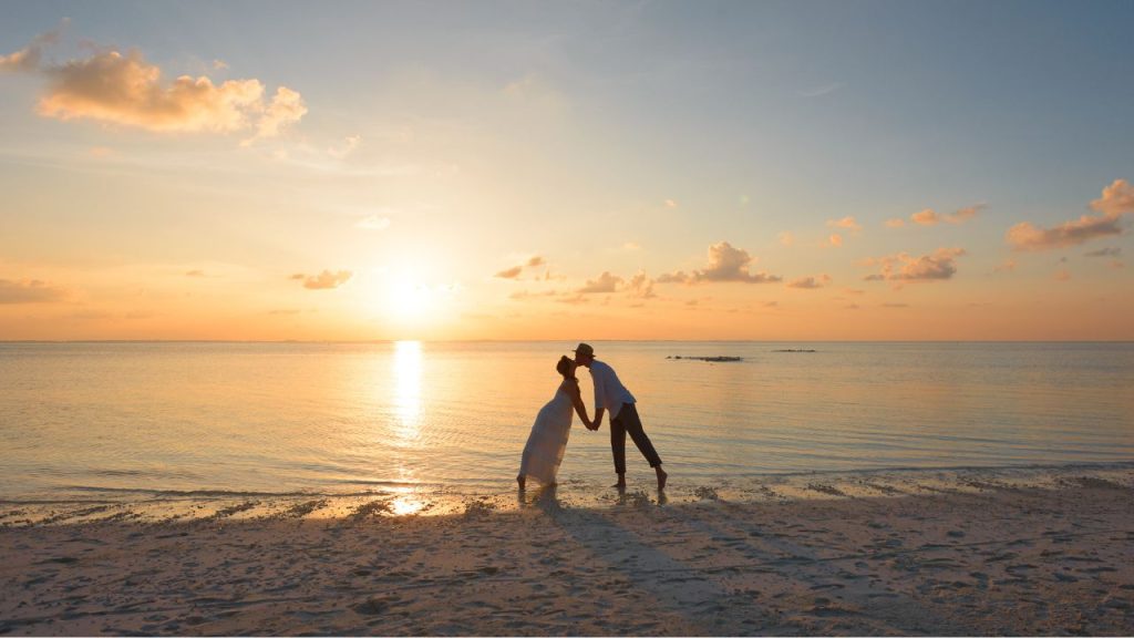 夕暮れの海辺でキスをするカップル