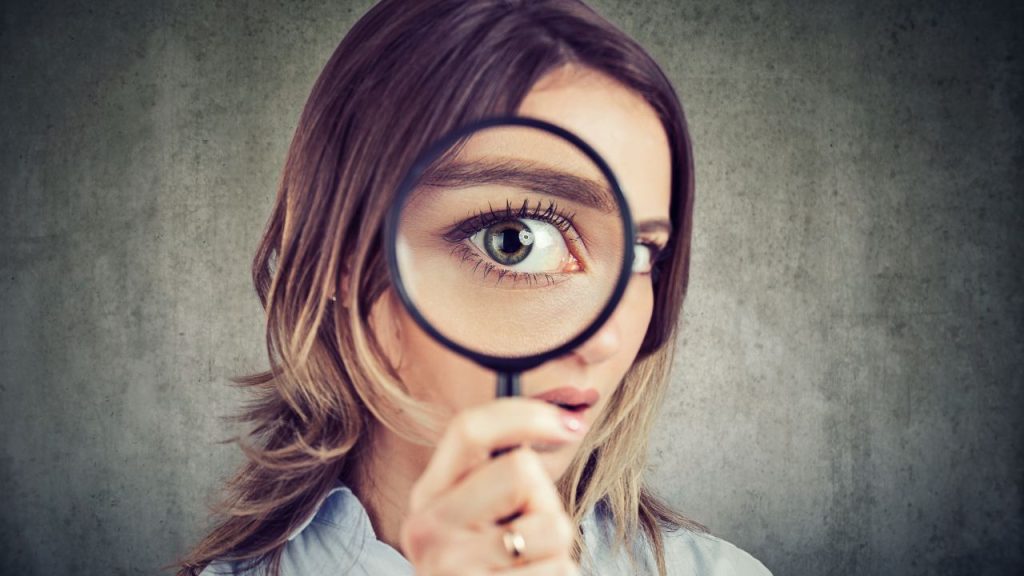 虫眼鏡で人を見極めようとしている画像